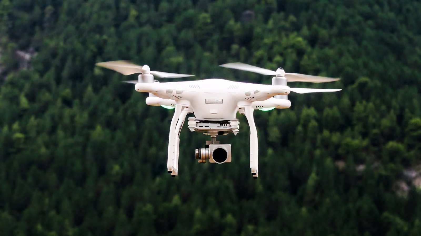 Dron blanco volando sobre un bosque
