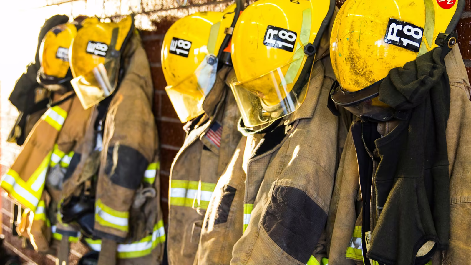 Trajes de bombero y cascos amarillos colgados en una estación