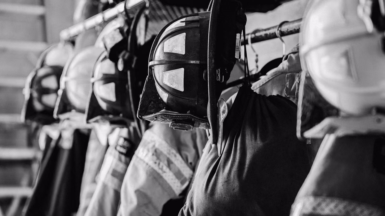 Cascos y trajes de bombero colgados en fila dentro de una estación