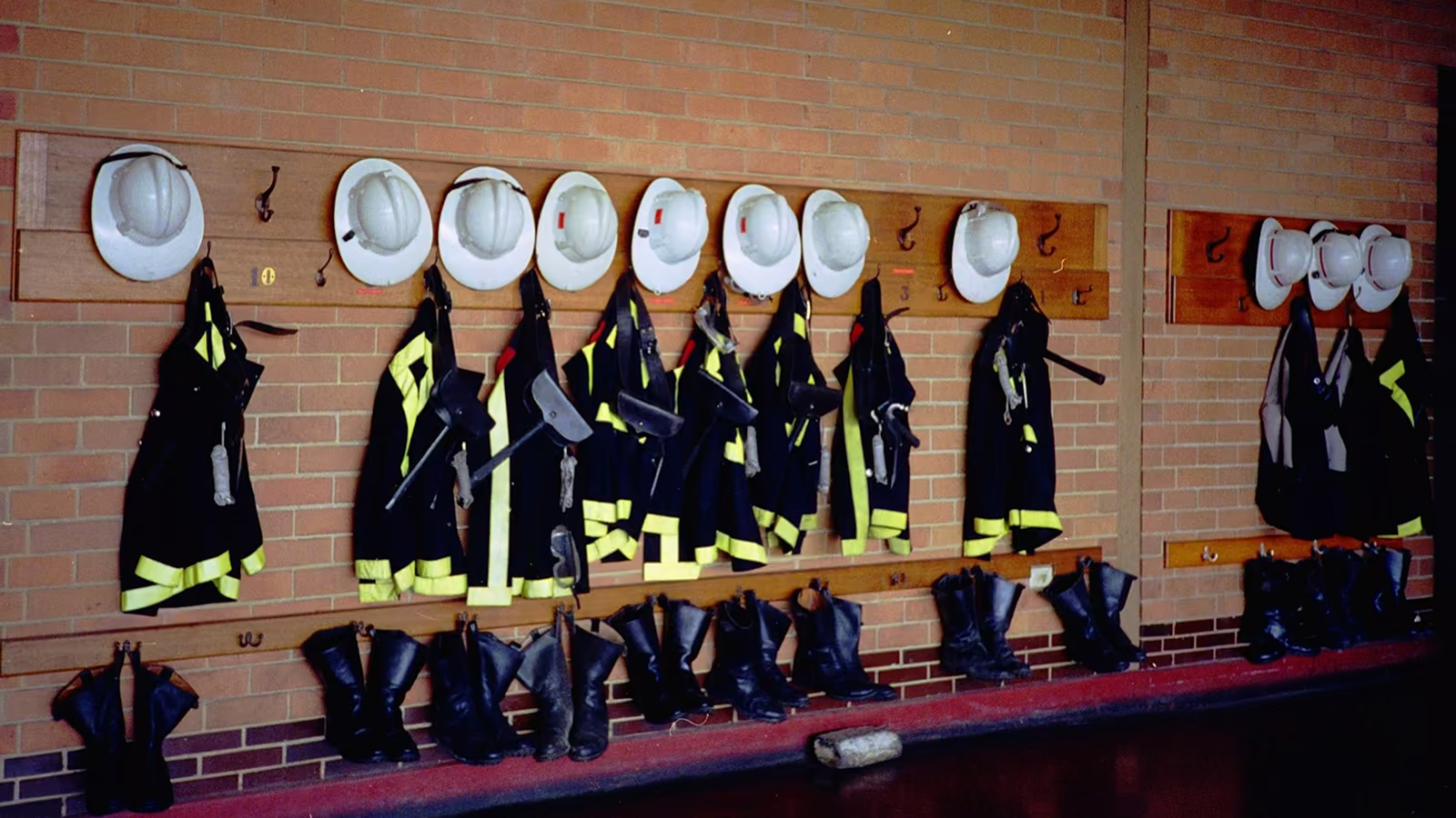 Trajes de bombero y cascos colgados en perchero de una estación