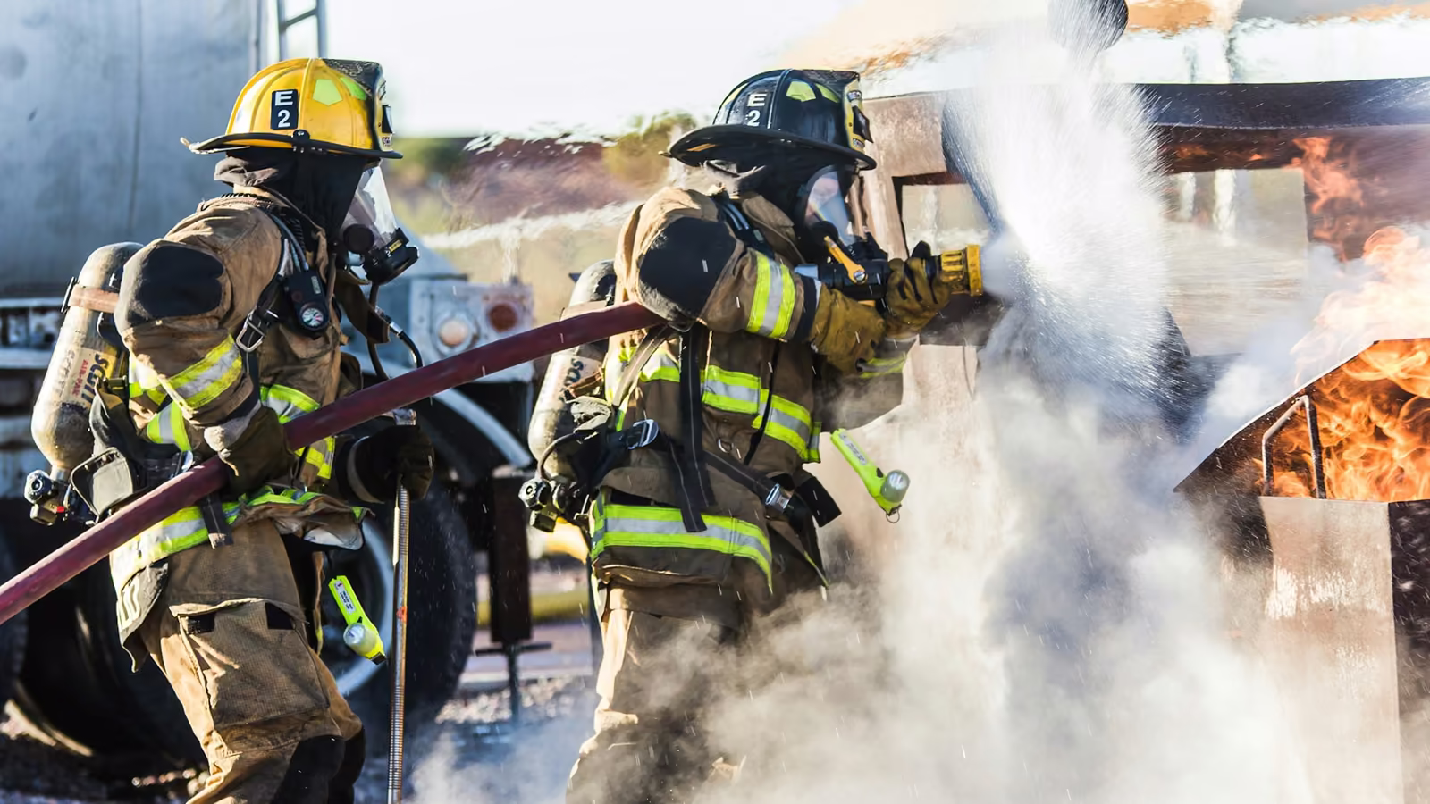 Bomberos con equipo de protección combatiendo un incendio con manguera